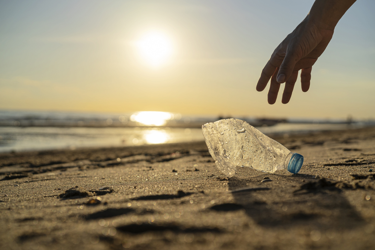 volunteer man and plastic bottle, clean up day, collecting waste on sea beach