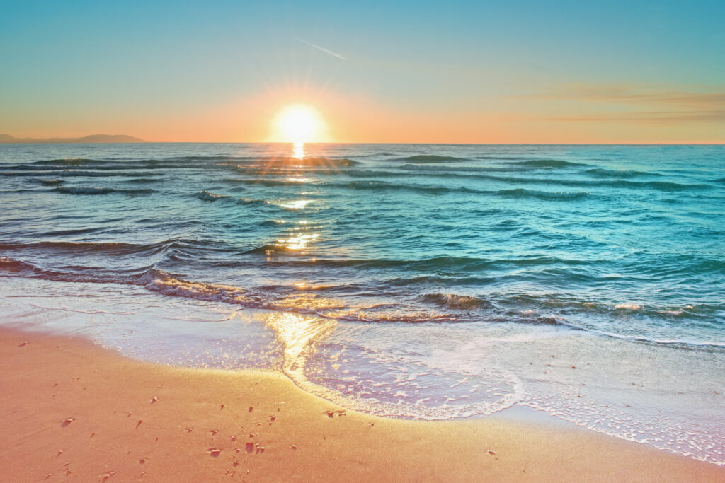 colorful sunset viewed from the pink sea beach with soft waves